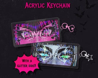 May include: Two rectangular Monster High acrylic keychains measuring 2.75 inches. One features pink eyes with bat motifs, the other blue eyes with lightning bolts and stitches. Both include a pink heart-shaped or black star-shaped metal clasp.