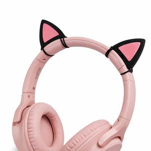 Può includere: Cuffie rosa wireless con orecchie da gatto. Le cuffie hanno una fascia e padiglioni imbottiti. Le orecchie da gatto sono nere con centri rosa. Progettate per ascoltare musica o altri contenuti audio.