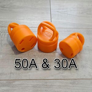 May include: Three orange electrical plug covers with handles. The covers are labeled "50A & 30A". The plugs have three prongs and are designed to protect electrical outlets from the elements.