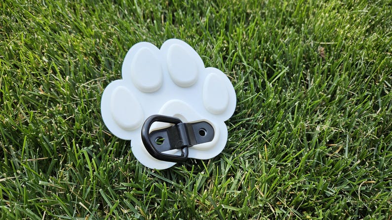 May include: White plastic paw print with a black metal D-ring attached. The paw print has five raised bumps.