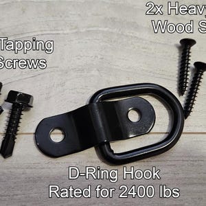 May include: A black metal D-ring hook rated for 2400 lbs, with three self-tapping metal screws and two heavy-duty wood screws.