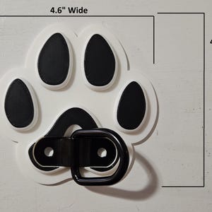 May include: White plastic paw print with black paw pads and a black metal D-ring. The paw print is 4.6 inches wide and 4.6 inches tall.