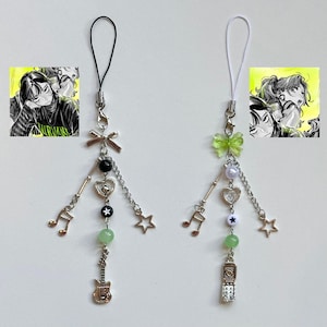 May include: Two phone charms with black and white strings. Each charm has a green clover, a silver heart, a silver music note, a silver star, a green stone, and a silver charm. One charm has a silver guitar and the other has a silver mobile phone.
