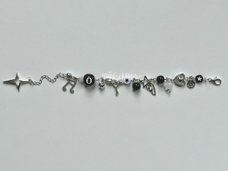 May include: A silver charm bracelet with black and white beads and charms, including a star, music note, key, heart, and wings.