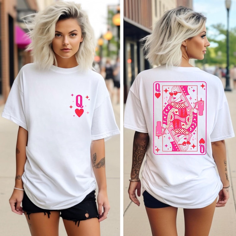 Puede incluir: Camiseta blanca con un gr&aacute;fico de la reina de corazones de la baraja de cartas rosa en la parte posterior y un peque&ntilde;o coraz&oacute;n rosa y un s&iacute;mbolo de reina en la parte delantera.