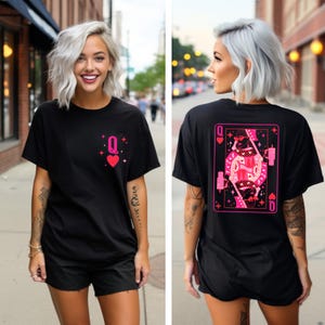 Puede incluir: Camiseta negra con un gr&aacute;fico de la reina de corazones de la baraja de cartas rosa en la parte posterior. La parte delantera de la camiseta tiene un gr&aacute;fico m&aacute;s peque&ntilde;o de la reina de corazones rosa.