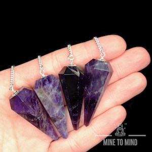 May include: Four amethyst crystal pendulums with silver chains. The pendulums are pointed and have a deep purple colour.