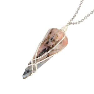 May include: A pendant necklace with a teardrop-shaped gemstone encased in silver-coloured wire. The gemstone displays pink, grey, and brown tones. The chain is a delicate silver-coloured link chain.