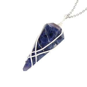 May include: A silver wire-wrapped pendant featuring a blue and purple gemstone. The pendant is attached to a silver chain.