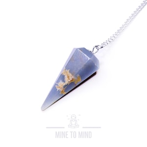 May include: A blue and white crystal pendulum with a silver chain. The crystal is a pointed cone shape with a light blue base and white and brown inclusions.