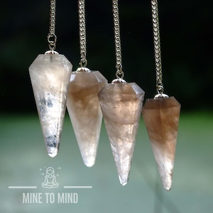 May include: Four brown and white crystal point pendulums with silver chains hanging against a dark background.