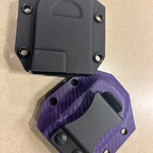 May include: Two holsters for a knife or other small tool. One is black and the other is purple with a carbon fiber pattern.