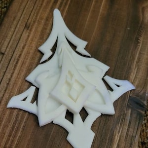 May include: White plastic ornament with a geometric design. The ornament is made up of several overlapping pieces, creating a layered effect.
