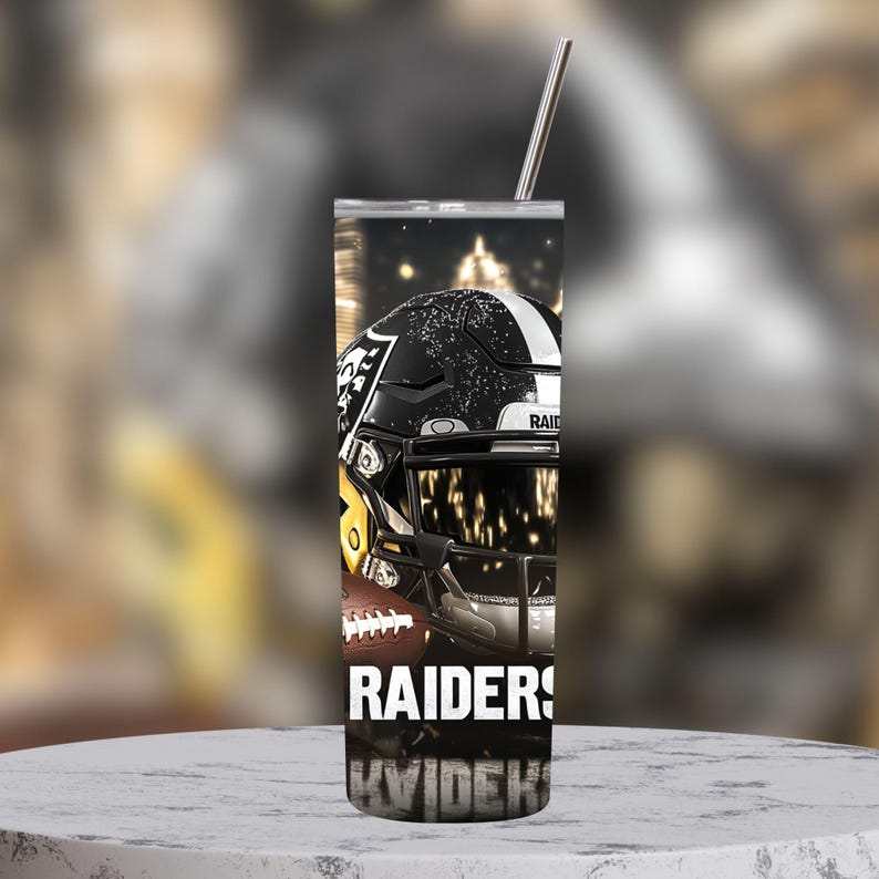K&ouml;nnte beinhalten: Ein schwarz-wei&szlig;er Edelstahlbecher mit einer Grafik eines Footballhelms und den Worten "RAIDERS" und "KVIDENK".