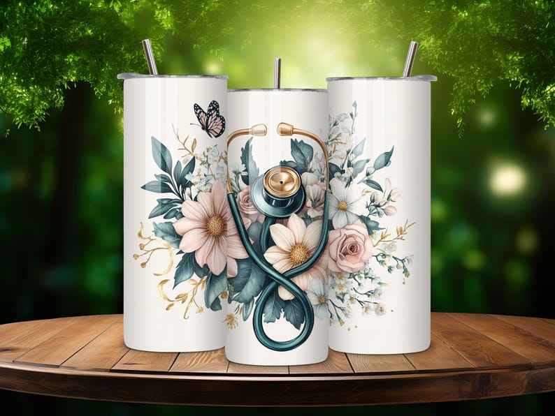 Puede incluir: Tres vasos de acero inoxidable con fondo blanco y un dise&ntilde;o floral con un estetoscopio y una mariposa. Los vasos est&aacute;n sobre una mesa de madera.