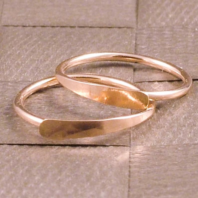Puede incluir: Dos anillos dorados con un dise&ntilde;o plano y rectangular en la parte delantera. Los anillos son simples y elegantes, con un acabado liso y pulido. Los anillos probablemente est&aacute;n hechos de oro o metal dorado.