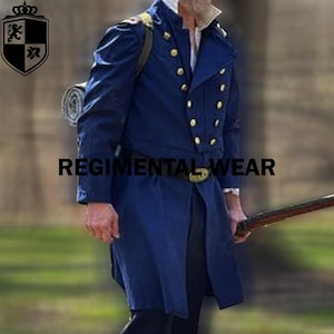 Könnte beinhalten: Ein marineblauer Mantel im Militärstil mit goldenen Knöpfen und passendem Gürtel. Der Mantel hat ein doppelreihiges Design und den Text "REGIMENTAL WEAR". Eine zusammengerollte Decke wird über der Schulter getragen.