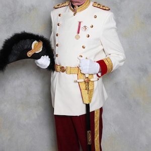 May include: A person in a white military uniform with gold detailing, red trim, and gold buttons. The uniform includes a decorative belt, a sword, and a black feathered fan. The person is wearing white gloves.