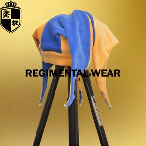 Pode incluir: Um chapéu de bufão azul e amarelo com sinos nas pontas dos pontos. O chapéu está em um tripé.