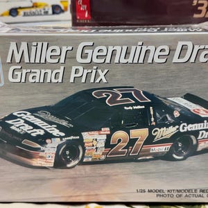 May include: A 1/25 scale model kit of a black and gold Miller Genuine Draft race car with the number 27 on the side. The box features the car's sponsor, Miller Genuine Draft, and the words "Grand Prix".