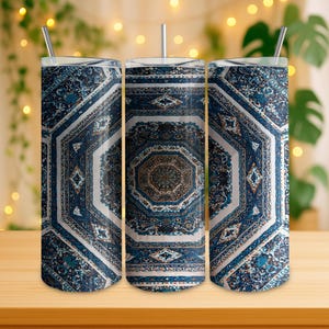 Può includere: Tre bicchieri in acciaio inossidabile con coperchi e cannucce. I bicchieri presentano un motivo ottagonale dettagliato nei toni del blu, bianco e marrone, che ricorda un design di tappeto tradizionale. I bicchieri sono posizionati su una superficie di legno.