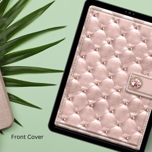 May include: A pink and white quilted tablet case with a diamond-shaped pattern and a small pink jewel accent. The case has a black border and a flap with a button closure. "Front Cover" is written in white text below the case.