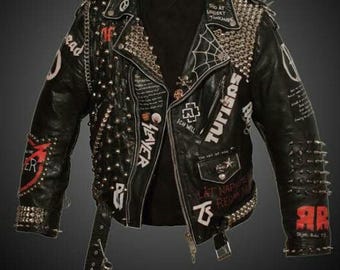 May include: Black leather jacket with silver studs and spikes. The jacket has various patches and writing, including "TUTISAS", "LAYER", "ICH WILL", and "THE ART OF WAR".