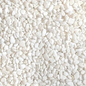 May include: A close-up image of white pebbles. The pebbles are small and smooth, and they are arranged in a random pattern. The pebbles are a light white colour, and they have a slightly glossy finish.