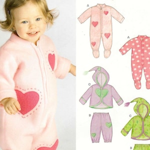 May include: A sewing pattern envelope featuring illustrations of infant clothing including footed sleepers with heart motifs, a hooded jacket with a heart design, and matching trousers. The pattern displays variations labelled A, B, and C with different prints.