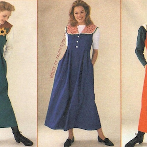 May include: Three sleeveless jumper dresses in teal, blue, and orange. The teal dress features sunflower appliques on the shoulders. The blue dress has a pink scalloped collar. The orange dress displays a pine tree pattern on the collar.