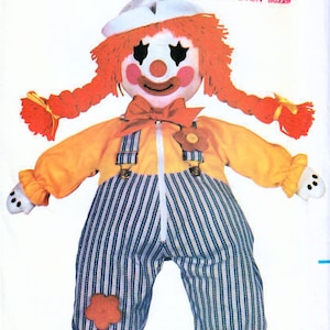 May include: A vintage sewing pattern for a clown doll. The pattern is from Butterick and is number 3510. The doll is wearing a yellow shirt with a blue and white striped jumpsuit, a red bow tie, and red shoes. The doll has red hair in pigtails and a white hat.