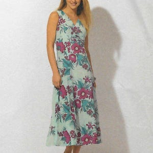 May include: A sleeveless, V-neck dress with a floral pattern. The dress has a light blue background with large, magenta flowers and teal accents. The knee-length dress appears to be made of a lightweight fabric.