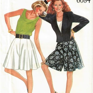 May include: A sewing pattern for two different styles of shorts. The first style is a white, pleated, A-line short. The second style is a black and white floral print short with a cuffed hem. The pattern is from New Look and the pattern number is 6084.
