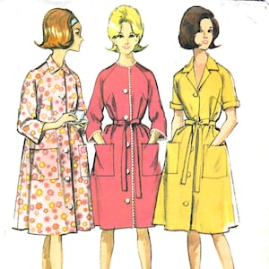 May include: A vintage sewing pattern illustration featuring three knee-length housecoats. One is white with a pink and orange floral print, one is solid pink with white trim, and one is solid yellow. Each coat has a collar, buttons, and pockets.