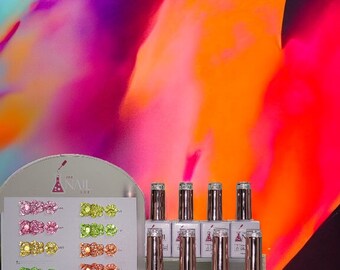 May include: A display of eight small bottles of clear gel nail polish with rose gold caps. The bottles are arranged on a clear acrylic shelf. The bottles are labeled "The Nail Lab Gel Polish".  A white card with rows of colorful glitter swatches is behind the bottles.