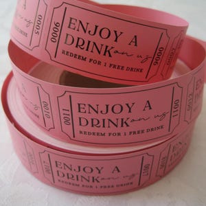 Puede incluir: Rollos de billetes de papel rosa con el texto "Enjoy a Drink" y "Redeem for 1 Free Drink".