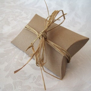 May include: A brown pillow box tied with a natural twine bow. The box is ready for gift giving.