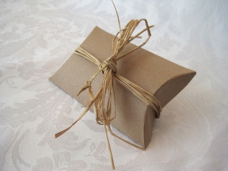 May include: A brown pillow box tied with a natural twine bow. The box is ready for gift giving.