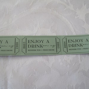 Puede incluir: Tres tickets de bebida de papel verde con el texto "ENJOY A DRINK on us" y "REDEEM FOR 1 FREE DRINK". Los n&uacute;meros de los tickets son 0002, 0003 y 0004.