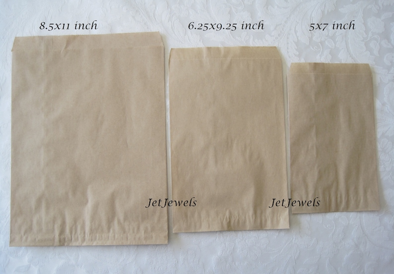 May include: Three brown paper bags of different sizes. The bags are labeled with their dimensions in inches: 8.5x11 inch, 6.25x9.25 inch, and 5x7 inch. The bags are on a white surface. The text "Jet Jewels" is printed on the bottom of the two larger bags.