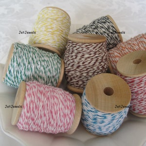 Puede incluir: Una colecci&oacute;n de carretes de hilo de colores con n&uacute;cleos de madera. El hilo est&aacute; disponible en varios colores, incluyendo amarillo, verde, rosa, azul, naranja, marr&oacute;n y negro, con detalles en blanco. Los carretes est&aacute;n dispuestos sobre un plato blanco decorativo.