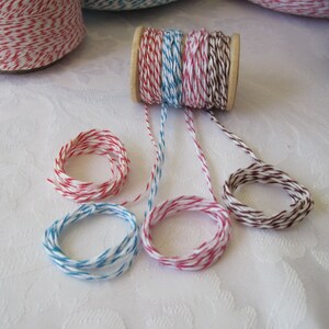 Puede incluir: Surtido de carretes y paquetes de hilo de colores. El hilo es de varios colores, incluyendo rojo y blanco, azul y blanco, rosa y blanco, y marr&oacute;n y blanco. El hilo est&aacute; enrollado en carretes de madera y tambi&eacute;n formado en peque&ntilde;os paquetes.