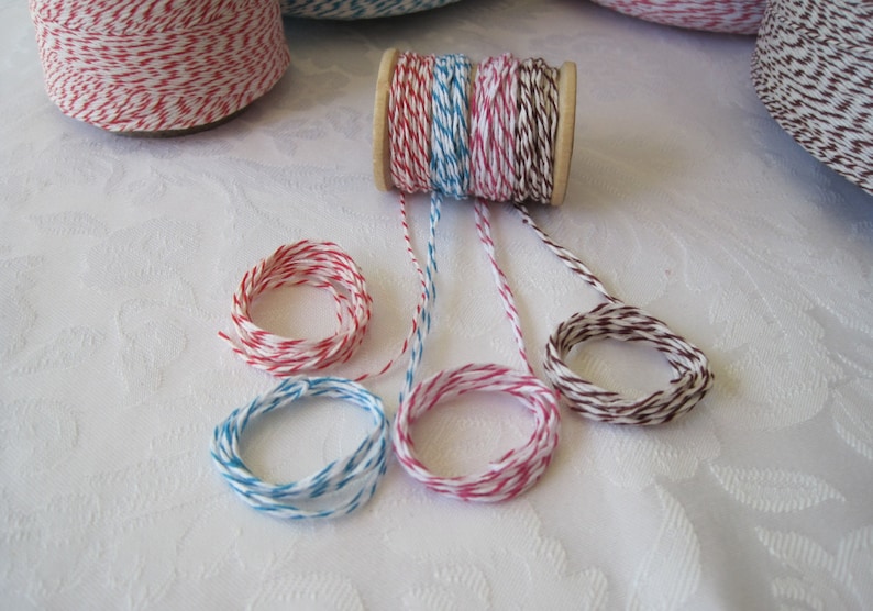 Puede incluir: Surtido de carretes y paquetes de hilo de colores. El hilo es de varios colores, incluyendo rojo y blanco, azul y blanco, rosa y blanco, y marr&oacute;n y blanco. El hilo est&aacute; enrollado en carretes de madera y tambi&eacute;n formado en peque&ntilde;os paquetes.