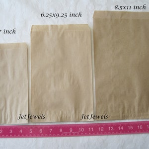 May include: Three brown paper bags of different sizes, 5x7 inches, 6.25x9.25 inches, and 8.5x11 inches, laid out on a white surface with a pink ruler underneath. The bags are labeled with the size and "Jet Jewels".