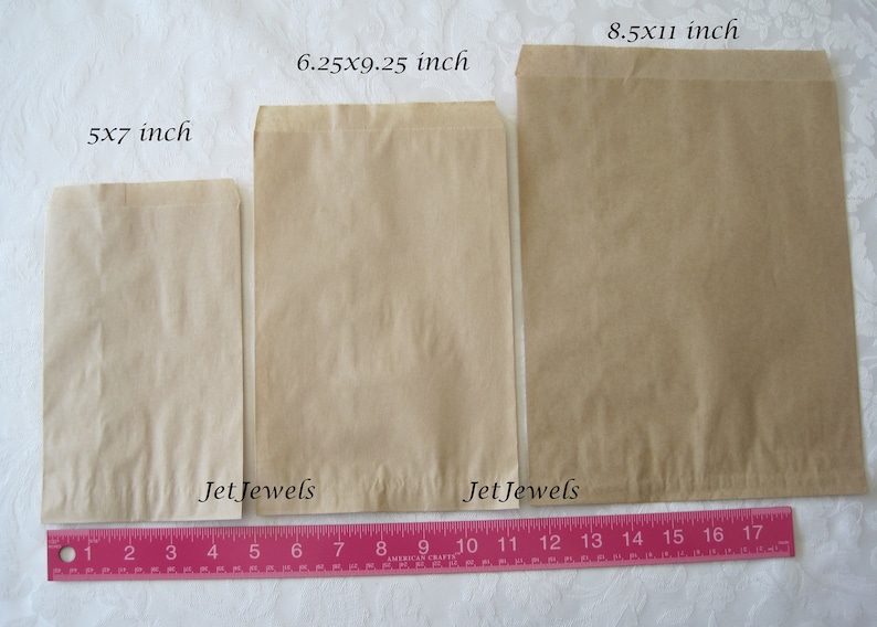 May include: Three brown paper bags of different sizes, 5x7 inches, 6.25x9.25 inches, and 8.5x11 inches, laid out on a white surface with a pink ruler underneath. The bags are labeled with the size and "Jet Jewels".