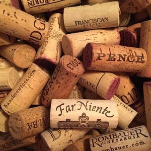 May include: A collection of used wine corks, featuring various brands and years. The corks are primarily light brown with printed text in black and red, including "PENCE" and "Far Niente".
