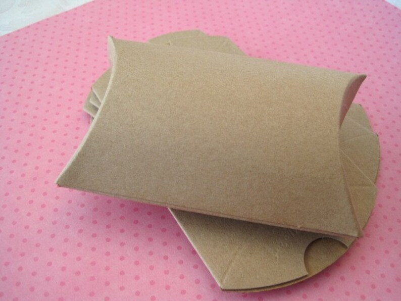 May include: A stack of brown cardboard pillow boxes. The boxes are folded and ready to be used for packaging small items.