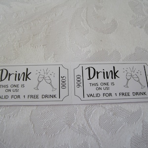 Puede incluir: Dos tickets de bebida blancos con texto negro y un gr&aacute;fico de dos copas de champ&aacute;n brindando. El texto dice "Drink This one is on us! Valid for 1 free drink".
