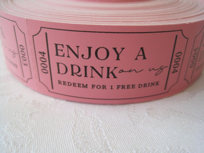 Op de afbeelding: Roze rol met tickets met de tekst "ENJOY A DRINK on us" en "REDEEM FOR 1 FREE DRINK".