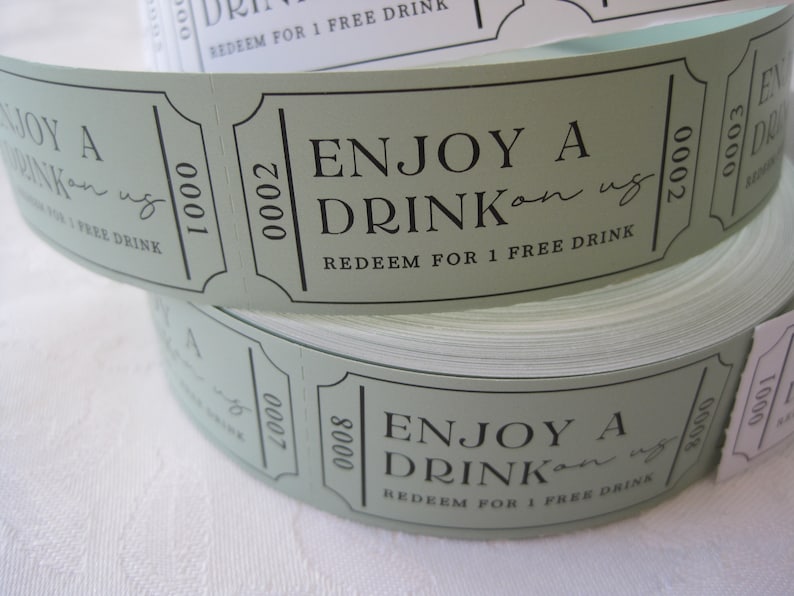 Puede incluir: Un rollo de tickets de bebida de papel verde con el texto "Enjoy a Drink on us" y "Redeem for 1 free drink".